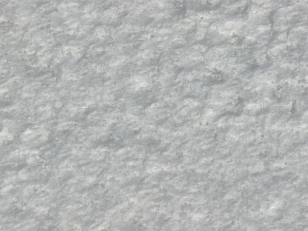 Rough ice texture, made up of bright white snow and dark, reflective chunks of ice.